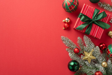 Christmas Day concept. Top view photo of pine branch in frost decorated with star ornament gold green red baubles and present box with ribbon bow on isolated red background with blank space