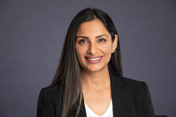 Studio headshots of beautiful Asian Indian woman in business attire on gray background. 