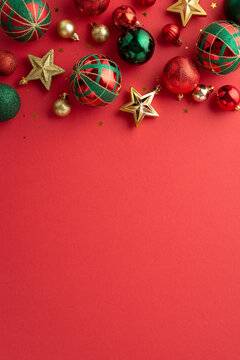 Christmas aesthetic concept. Top view vertical photo of star ornaments confetti gold green and red baubles on isolated red background with copyspace