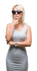 Fototapeta premium Young beautiful blonde woman wearing sunglasses over isolated background with hand on chin thinking about question, pensive expression. Smiling with thoughtful face. Doubt concept.