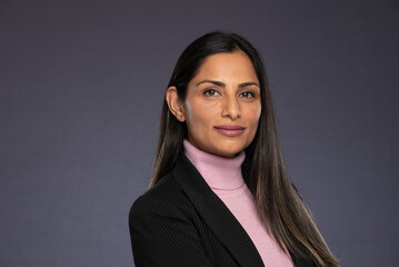 Studio headshots of beautiful Asian Indian woman in business attire on gray background. 