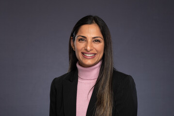 Studio headshots of beautiful Asian Indian woman in business attire on gray background. 