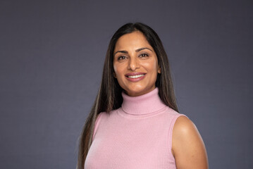 Studio headshots of beautiful Asian Indian woman in business attire on gray background. 