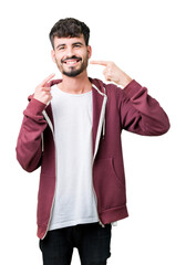Young handsome man over isolated background smiling confident showing and pointing with fingers teeth and mouth. Health concept.