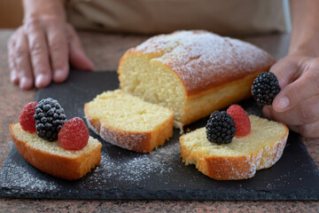 Close-up on woman hands decorating the homemade plumcake ready to eat. Cooking at home. Delicious healthy homemade dessert served with berries