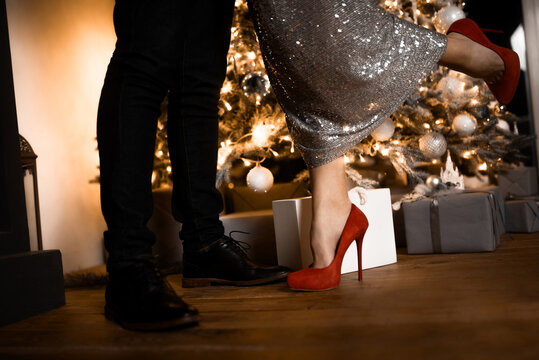 close-up of the legs of a man and a woman in shoes on the background of christmas decorations