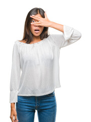 Fototapeta premium Young asian woman over isolated background peeking in shock covering face and eyes with hand, looking through fingers with embarrassed expression.