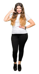 Young beautiful woman wearing casual white t-shirt smiling doing phone gesture with hand and fingers like talking on the telephone. Communicating concepts.