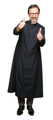 Middle age priest man wearing catholic robe approving doing positive gesture with hand, thumbs up...