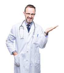 Middle age senior hoary doctor man wearing medical uniform isolated background smiling cheerful presenting and pointing with palm of hand looking at the camera.