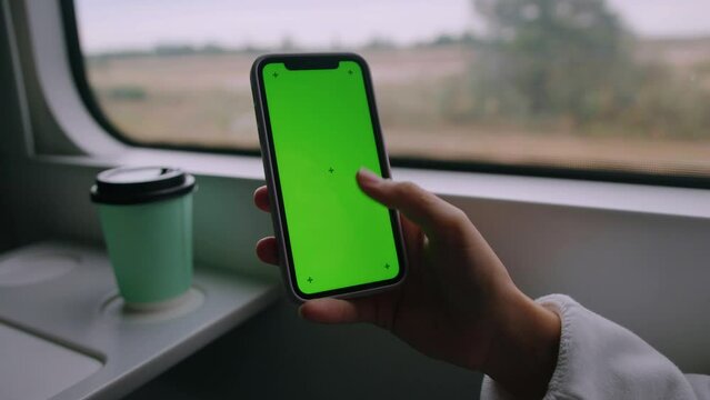 Close-up of the hand of a woman who runs her finger over the green screen of the phone. A place to advertise on a smartphone