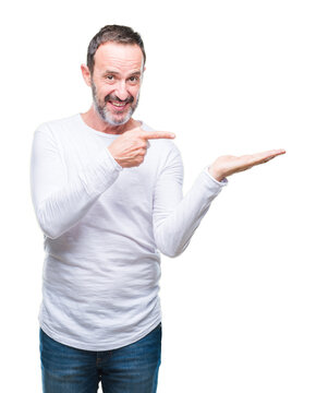 Middle age hoary senior man wearing white t-shirt over isolated background amazed and smiling to the camera while presenting with hand and pointing with finger.