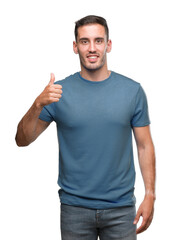 Handsome young casual man doing happy thumbs up gesture with hand. Approving expression looking at the camera with showing success.