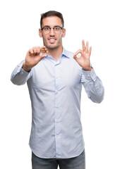 Handsome young man holding bitcoin doing ok sign with fingers, excellent symbol