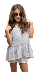 Naklejka premium Brunette hispanic girl wearing sunglasses looking confident with smile on face, pointing oneself with fingers proud and happy.