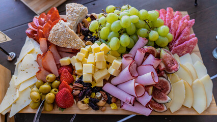 Food tray with delicious salami, sliced ​​pieces of ham, sausage, tomatoes, red berries, grapes and bread. appetizer.