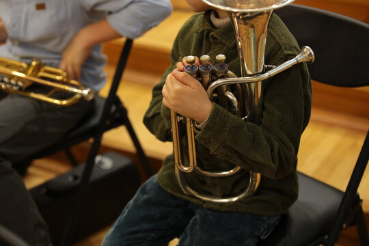 Child boy musician sitting in a classroom with a musical instrument tuba at a school music lesson in a jazz band.Background image close-up concept of education leisure and development of children