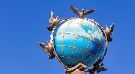 Globe with doves on a blue sky background. Globe planet earth.