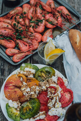  view of picnic table meal: caprese salad, baguette, spot prawns and lemon wedges 
