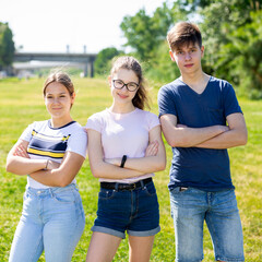 Obraz premium Cheerful teen friends having fun spending time outdoors in summer, posing with arms crossed on green lawn