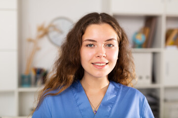 Portrait of european doctor female in blue shirt standing in white medical office in clinic