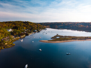 Cold Spring Harbor, New York with sandbar, woods, and various boats in the water.