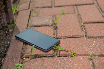 Smartphone on pavement outdoors, space for text. Lost and found