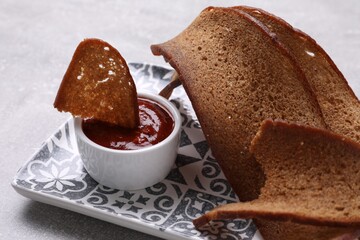 Plate with crispy rusks and dip sauce on light table, closeup