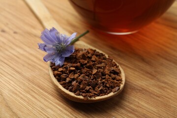Spoon of chicory granules with flower on wooden table, closeup