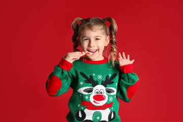 Cute little girl with Christmas gingerbread cookie on red background