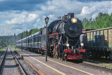 Naklejka premium Retro steam train approaches to the platform.