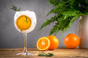 Gin tonic orange cocktail, long drink with dry gin, bitter tonic, rosemary and ice. Wooden table...