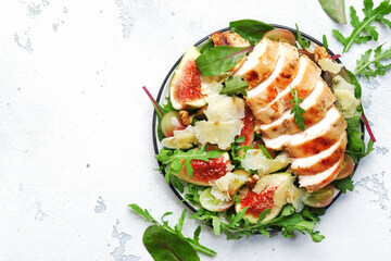 Grilled chicken fillet with fig, grape, arugula and chard salad. White kitchen table background, top view
