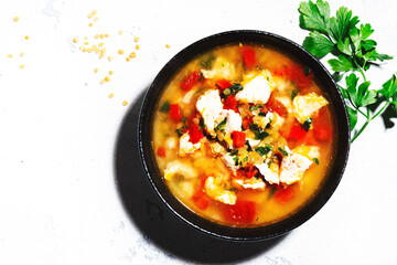 Warming autumn soup with red lentils, chicken fillet, vegetables, spices and paprika, comfort food. White table, hard light, top view
