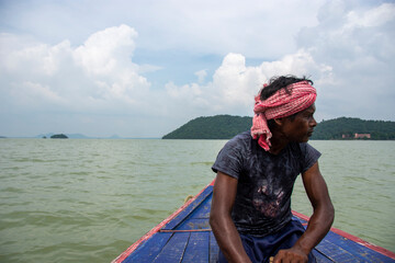 a poor tribal man pulling boat by his hand with paddle