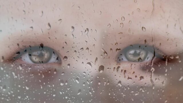 Close up   beautiful eyes looking through glass window with rain drops. Double exposure
