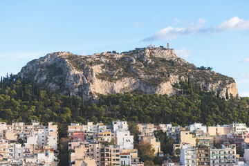 Fototapeta premium Athens, Attica, beautiful super-wide angle view of Athens, Greece, with Acropolis, Mount Lycabettus, mountains and scenery beyond the city, seen from Strefi Hill park in Exarcheia neighbourhood