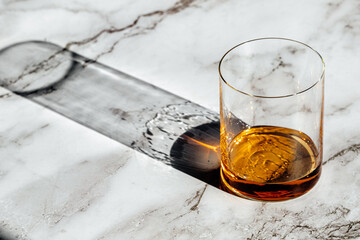 whiskey glass drink with sun light and shadow on a marble table 