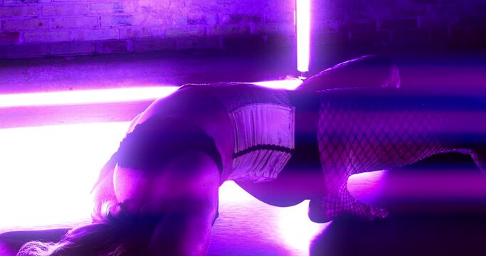 Contortionist In Purple Lit Room Bending Over Backwards To Lie On Floor