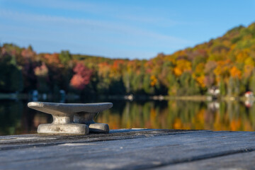 A cleat on dock waits for a boat to tie up on this small lake.