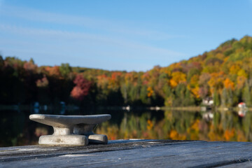 A cleat on dock waits for a boat to tie up on this small lake.