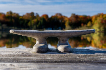 A cleat on dock waits for a boat to tie up on this small lake.