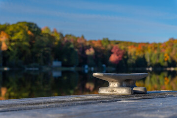A cleat on dock waits for a boat to tie up on this small lake.