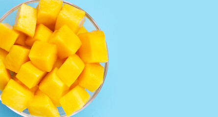Tropical fruit, Mango cube slices in white bowl on blue background. Copy space