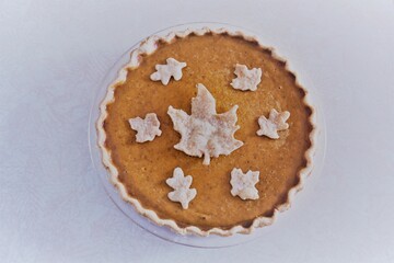 Top view of a freshly baked pumpkin pie with leaf shaped pastry cutouts on top