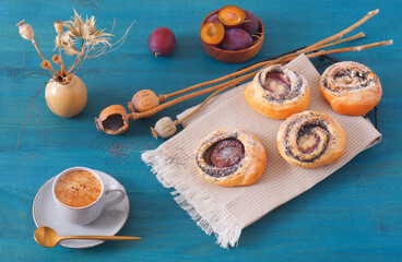 Mini pies filled with ground poppy seeds with fresh plums on  blue wooden table, High angle of view, no people.