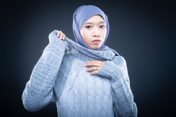 Portrait of a beautiful female model wearing hijab, a lifestyle apparel for Muslim women isolated on brown background. Idul Fitri and hijab fashion concept. Isolated on dark background