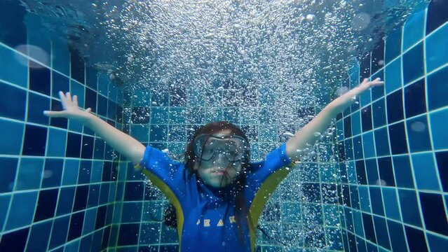 Bangi, Malaysia Kid dropping into swimming pool with bubles surrounding slow motion.