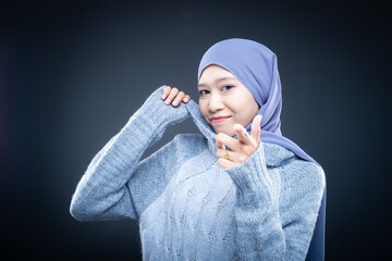 Portrait of a beautiful female model wearing hijab, a lifestyle apparel for Muslim women isolated on brown background. Idul Fitri and hijab fashion concept. Isolated on dark background