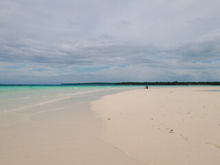 Fototapeta na wymiar Beautiful sunny day on a calm pristine beach with grey skies in Indonesia